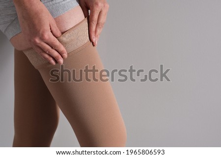 Woman is putting on lymphedema compression stockings