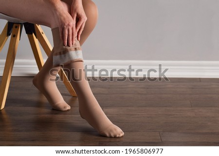 Woman is putting on lymphedema compression stockings