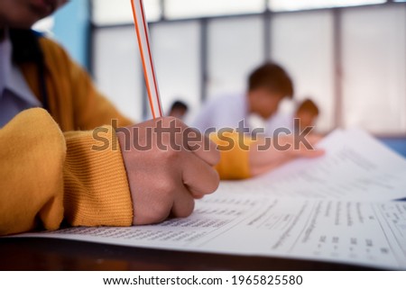 Students writing and reading exam answer sheets exercises in classroom of school with stress