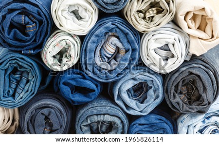 background from stack of different rolled jeans. Roll blue denim jeans arranged in stack. Jeans pyramid. Recycling old blue jeans on wooden table. Denim upcycle. Zero waste Royalty-Free Stock Photo #1965826114