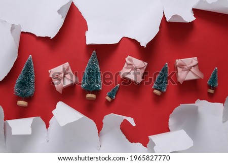 Gift boxes with mini Christmas tree and White Torn paper sheet on red background. Christmas, holiday background.