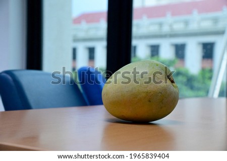 Closeup of Big Fresh Green Mango Fruit on wooden table with in the office background.