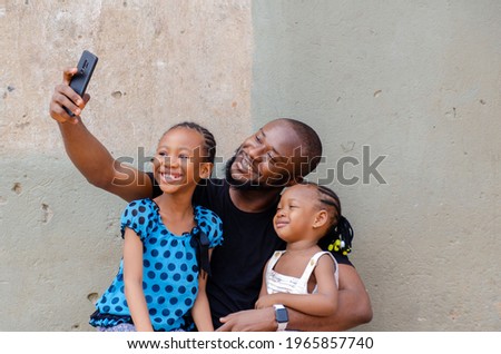 handsome african dad feeling excited with his daughters as they take a picture