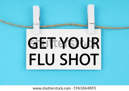 Medicine and health concept. On a blue background, a white plaque hangs on a rope with the inscription - GET YOUR FLU SHOT