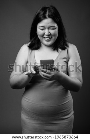 Beautiful overweight Asian woman against gray background