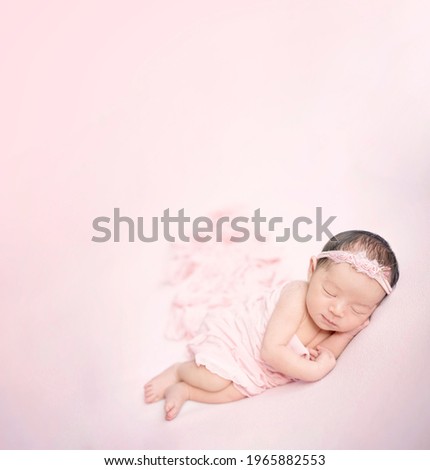 newborn baby sweet dreams wears a pink headband and pink swaddling with isolated pink background           