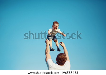 Summertime! Happy joyful child, father fun throws up son in the air, carefree, blue sky, family, travel, vacation, childhood, father's day - concept. Sunlight on the sunset Royalty-Free Stock Photo #196588463