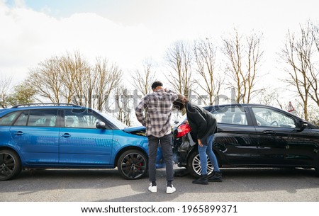 Young male and female drivers looking at damaged car hit from behind after traffic accident Royalty-Free Stock Photo #1965899371