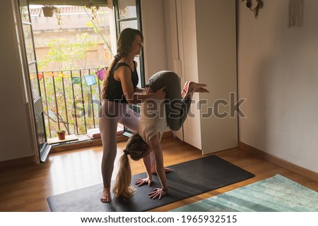 Yoga instructor helping her student to do a pose at home