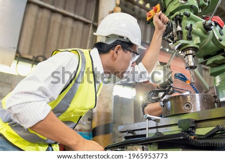 Asian mechanical engineer operating industrial lathe machine. Technicians and engineers are working on industrial machines. Royalty-Free Stock Photo #1965953773