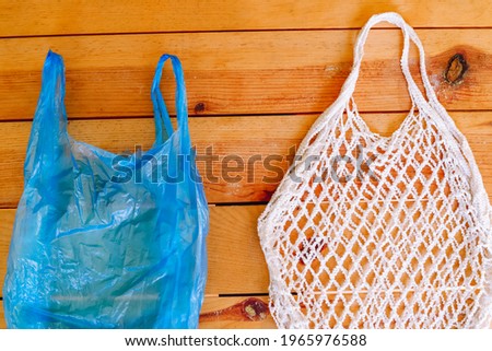 Environmentally harmful plastic bag and nature-friendly eco-friendly mesh bag on a brown wood background. Zero waste grocery shopping. Ban plastic. Choose plastic free.