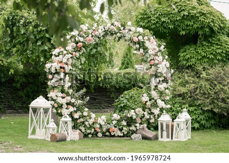 Wedding ceremony. Very beautiful and stylish wedding arch, decorated with various fresh flowers, standing in the garden. Wedding day. Fresh flowers decorations, Peony weddng. Royalty-Free Stock Photo #1965978724