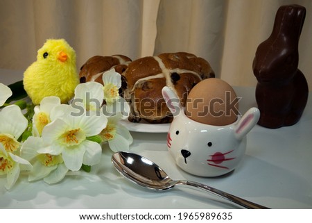 Easter eggs and baby chicks symbolize new life. A hot cross bun is a spiced sweet bun usually made with fruit, marked with a cross on the top, and traditionally eaten on Good Friday.