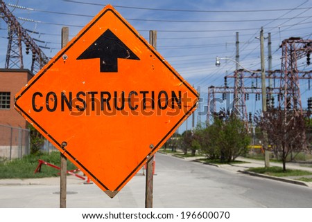 Bright Orange Construction sign by the of a road