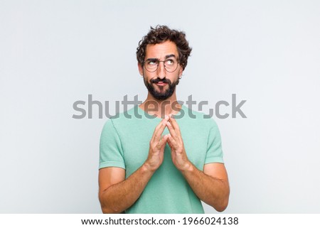 young bearded man scheming and conspiring, thinking devious tricks and cheats, cunning and betraying Royalty-Free Stock Photo #1966024138