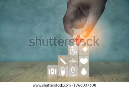 Hand of doctor arranging wood block stacking with illustration icon healthcare medical on table with concrete wall. Health Insurance Concept. Inspiration and new ideas