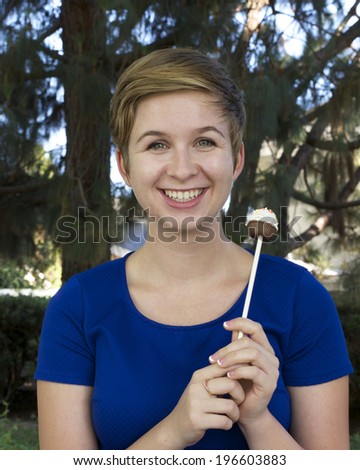 Model released image of Young caucasian Teenage Blonde Girl holding a cupcake cake pop on a stick fun treat for parties