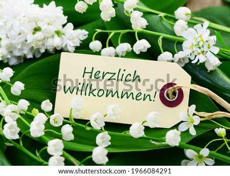 Herzlich willkommen! (Welcome!), card with flowers, closeup.
