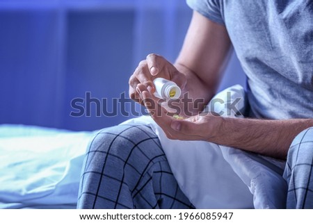 Young man taking sleeping pills at night Royalty-Free Stock Photo #1966085947