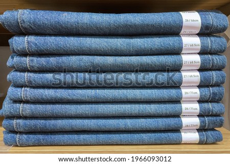 Neatly stacked blue jeans And there is a size label.