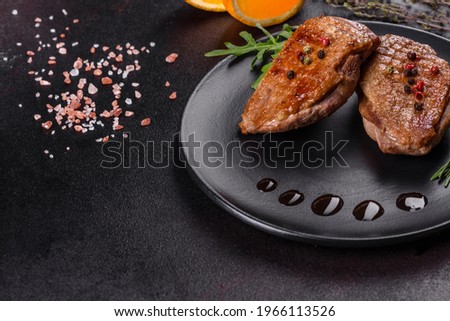 Baked duck breast with herbs and spices on a dark concrete background. Fried meat ready to eat
