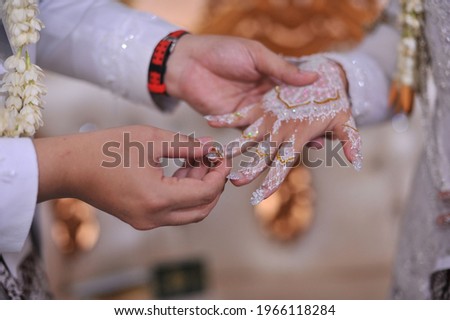 The man's hand (picture 2) who is putting the ring on his partner