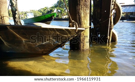Boat tied in wood, with landscape just behind.
