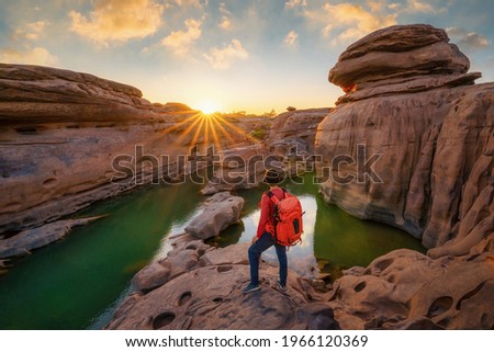 Back of tourist man, a backpacker people, travel in Sam Phan Bok, Ubon Ratchathani, Thailand. Dry rock with mountain hills. Nature landscape. Grand Canyon of Thailand. Adventure lifestyle activity. Royalty-Free Stock Photo #1966120369