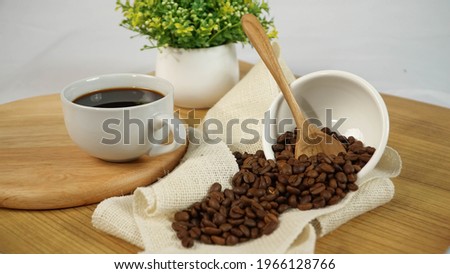 Fresh hot black coffee with robusta coffee beans and home decoration on wooden table
