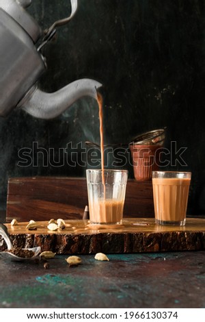 indian masala chai or tea ion ttraditional glasses, with kettle, spices and tea leaves. Royalty-Free Stock Photo #1966130374