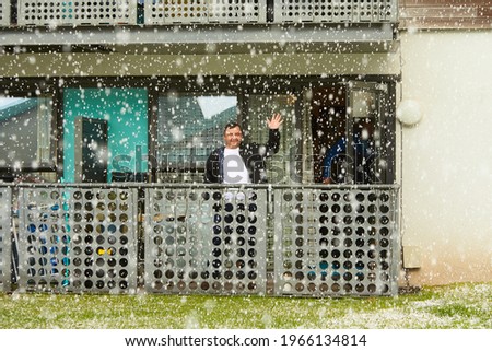 A man at the balcone in during snow.