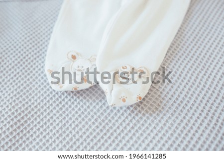 expecting a baby. parenting. preparing for the birth of a baby buying clothes. baby romper in beige with a pattern of a bunny on legs on a gray background.