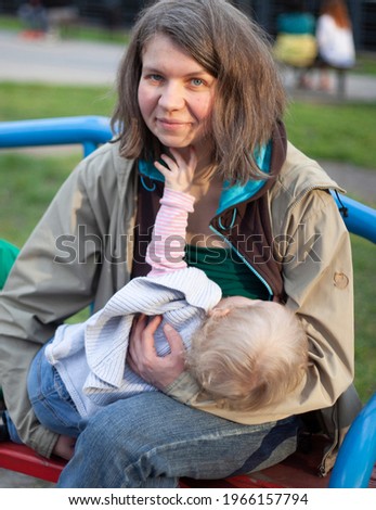 Mom breastfeeds daughter on a park bench Mom with a little daughter on the playground