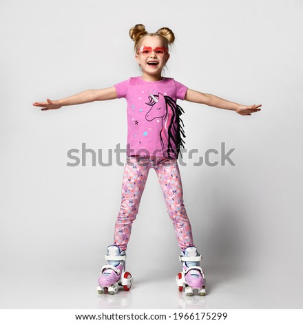 Full body portrait of positive funky little girl learning to ride on roller skates keeping balance enjoying fun isolated on white studio background. Happy childhood leisure activity concept