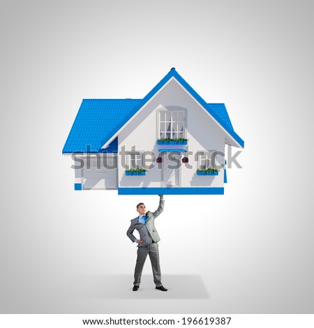 Young strong businessman lifting huge model of house above head