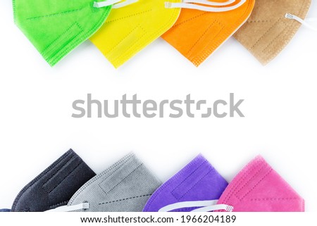 Row stack of  different colors FFP2 or N95 face masks respirators without exhalation valve on white background. Top view flat layer. Protection from covid virus during pandemic.