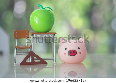 Creative minimalist photo of student desk, green apple and pig doll. The concept of back to school