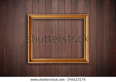 Golden picture frame on dark wooden wall