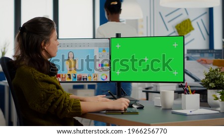 Woman retoucher working on photo set in photo editing software using greenscreen, chroma key isolated display of computer. Content creator doing portrait retouching in digital multimedia company
