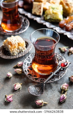 Turkish tea in traditional glasses with baklava on dark  background