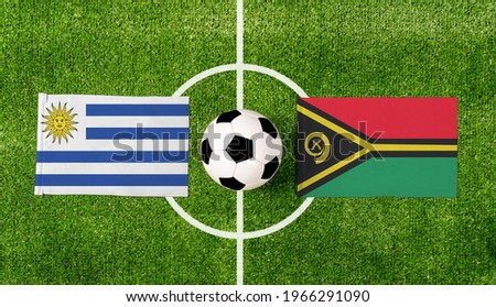 Top view ball with Uruguay vs. Vanuatu flags match on green football field.