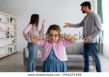 Childhood traumas concept. Upset arab girl covering ears with hands not to listen parents conflict, innocent child suffering from family preblems, selective focus. Witnessing domestic quarrels at home Royalty-Free Stock Photo #1966291468