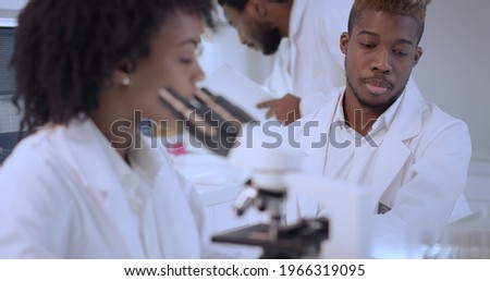 African ethnicity doctors working in laboratory.  Discussing, using microscope and computers