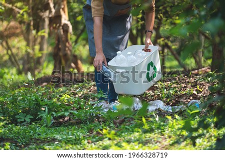 Closeup image of a woman collecting and putting plastic bottles into a recycle bin in the outdoors Royalty-Free Stock Photo #1966328719