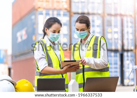 Group of Diversity factory worker women with face mask meeting to inspect containers logistic in local warehouse. asian, and white caucasian people operate on site cargo for logistic shipping area.