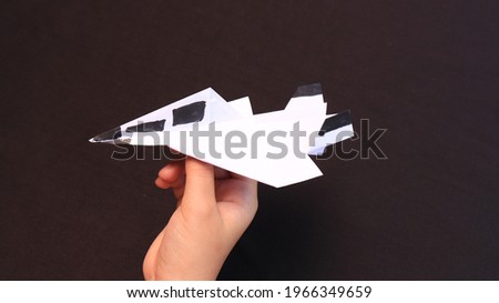 White and black toy airplane made of paper on isolated black background with copyspace
