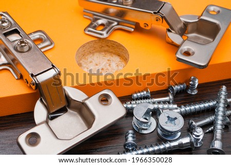 Closeup of various furniture fittings. Furniture assembly kit,  Concealed hinge and various screws on orange board. Royalty-Free Stock Photo #1966350028