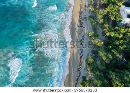An aerial shot of cliffs covered in greenery surrounded by the sea under the sunlight