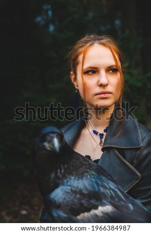 young woman or  girl in the forest with a big black raven on his hand