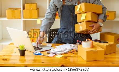 Entrepreneurs Small Business SME Independent men work at home Use smartphones and laptops for commercial checking, online marketing, packing boxes, SME sellers, concept, e-commerce team, online sales Royalty-Free Stock Photo #1966392937